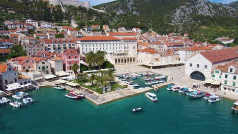 panorama of a coastal town with many houses with red roofs, surrounded by the sea and mountains with yachts in marina bay and bell tower