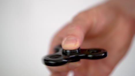 hand eines kaukasischen mannes, der beliebtes fidget-spinner-spielzeug in bewegung hält, slomo