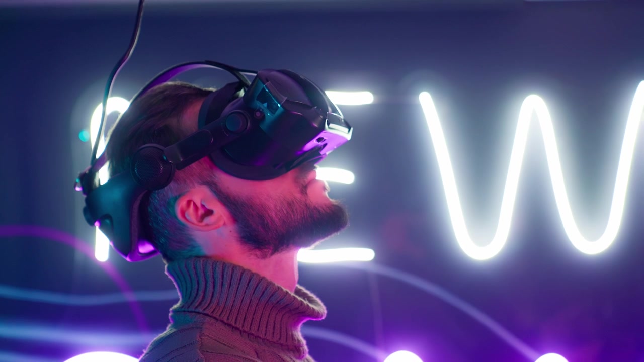 Man Wearing VR Headset Interacting with Virtual Reality in Neon Lit Room