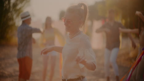 Fröhliche-Blonde-Frau-Mit-Sonnenbrille-Tanzt-Am-Strand