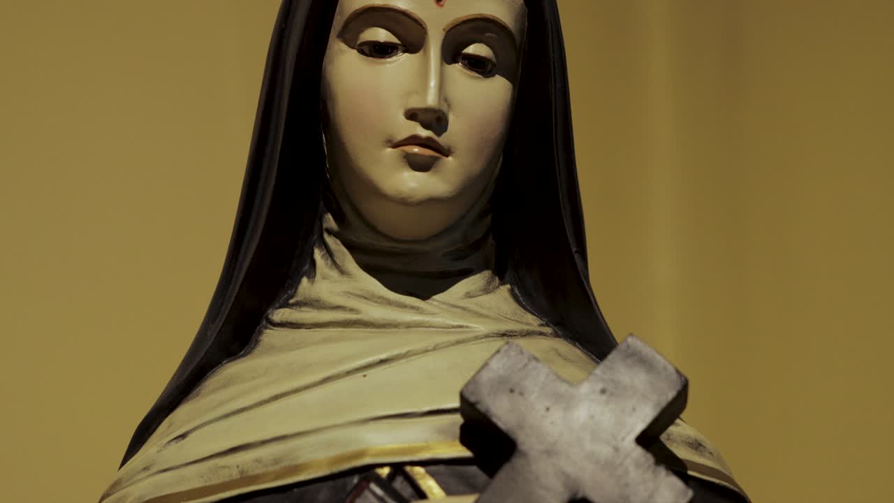 una estatua de la virgen maría con una cruz y una biblia en sus manos en una iglesia en europa central, capturada en resolución 4k