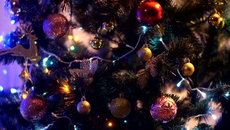 christmas balls with glitter hanging on a christmas tree on a dark background of green needles with flickering garlands. christmas decoration