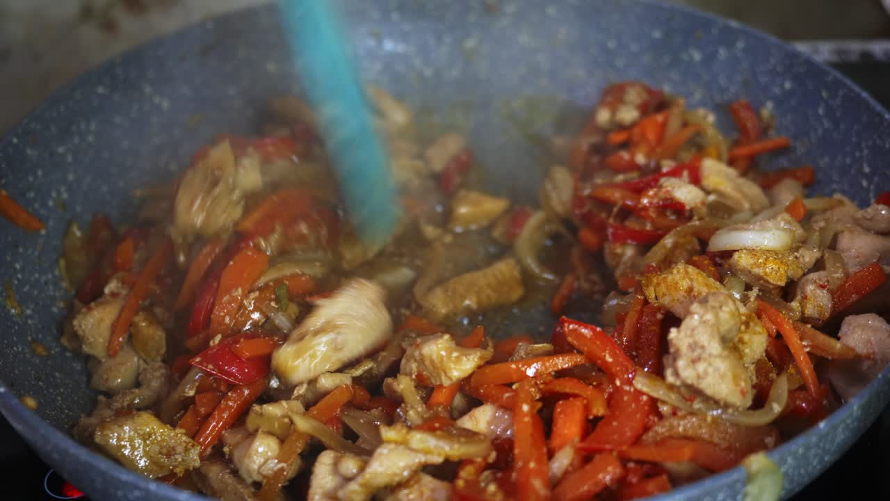 Vibrant stir-fry preparation featuring chicken and colorful vegetables cooking in a pan. A quick and appetizing demonstration of home cooking