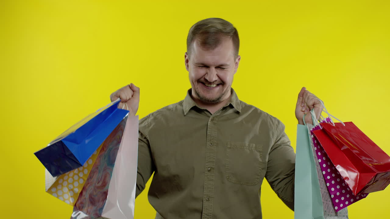 쇼핑 가방을 들어 올리는 남자, 구매에 만족하는 모습, 블랙 프라이데이에 할인을 즐기는 모습