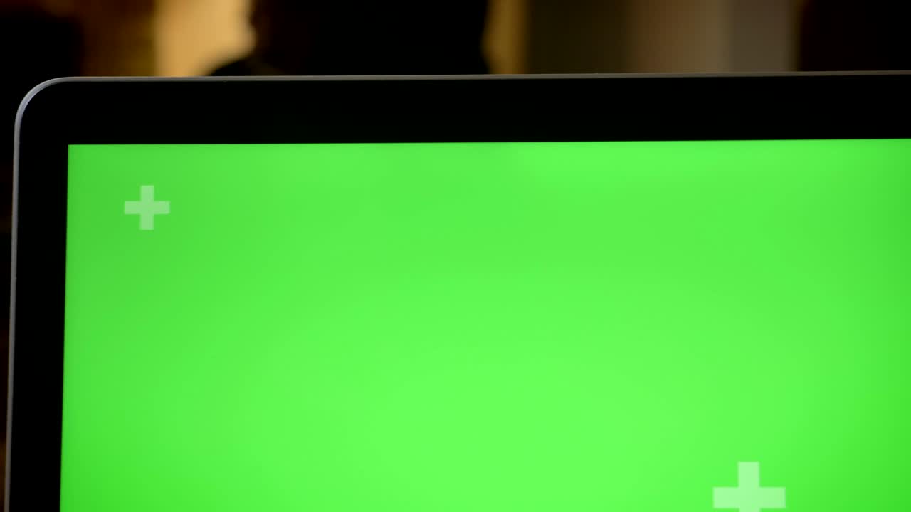 ripresa ravvicinata del portatile con schermo cromato verde sul tavolo con i dipendenti sullo sfondo sfocato in ufficio all'interno