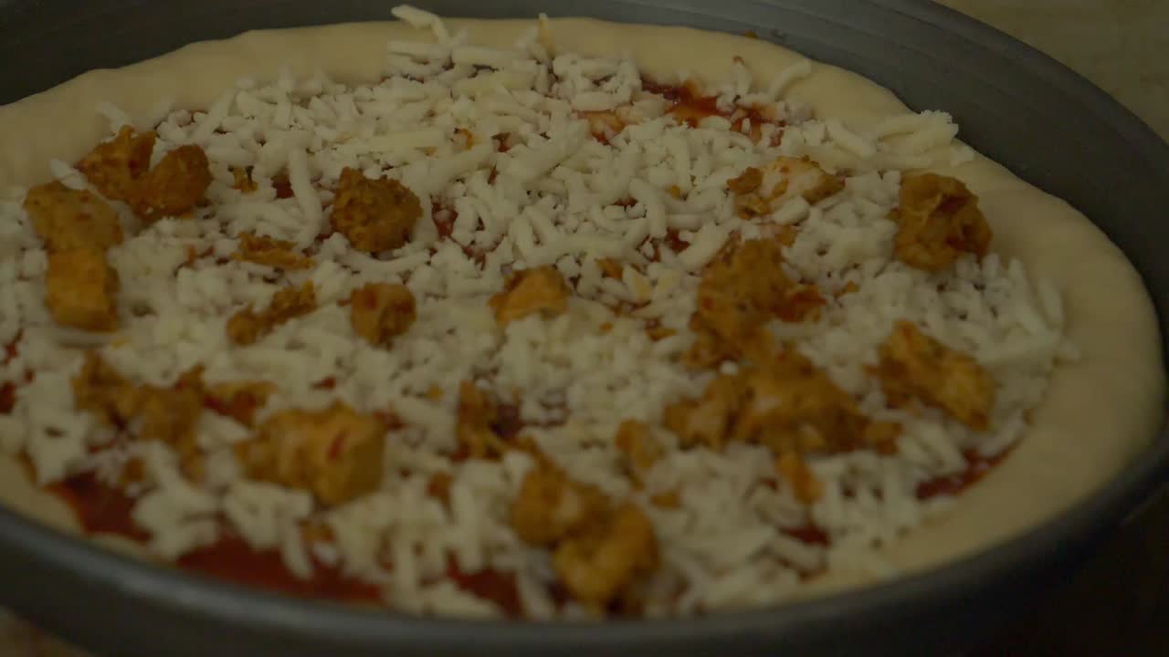 espolvorear a mano trozos de pollo sobre pizza fresca