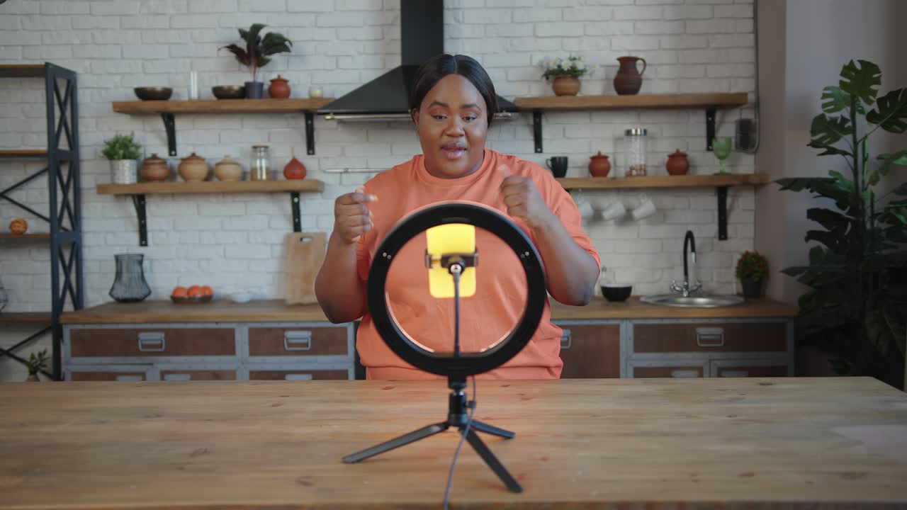 un blogger gordo con cola de caballo habla en un trípode con un teléfono inteligente