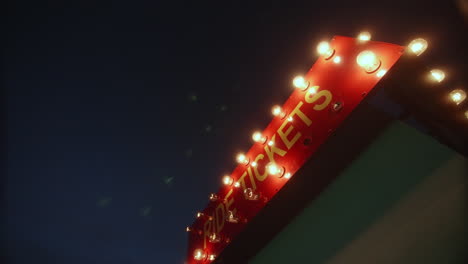 ride tickets booth sign with flashing lights at carnival, wide shot, dolly right, slow motion