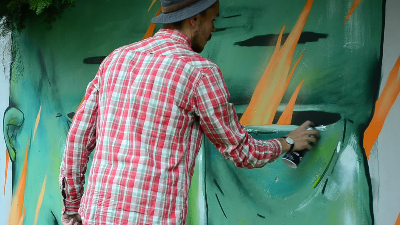 L'artista disegna graffiti su una recinzione.