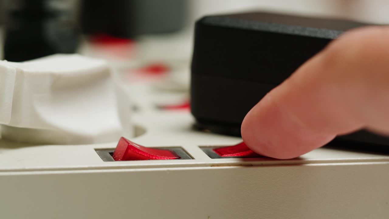 White power strip with many various of cords and cables in close-up. An extension cord with many power sockets. Adapter with phone, headphones, usb connectors.Tangled wires on table. Trying to untangle many messy cables.