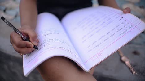 una chica con vestido corto está escribiendo notas con un bolígrafo en su cuaderno al aire libre