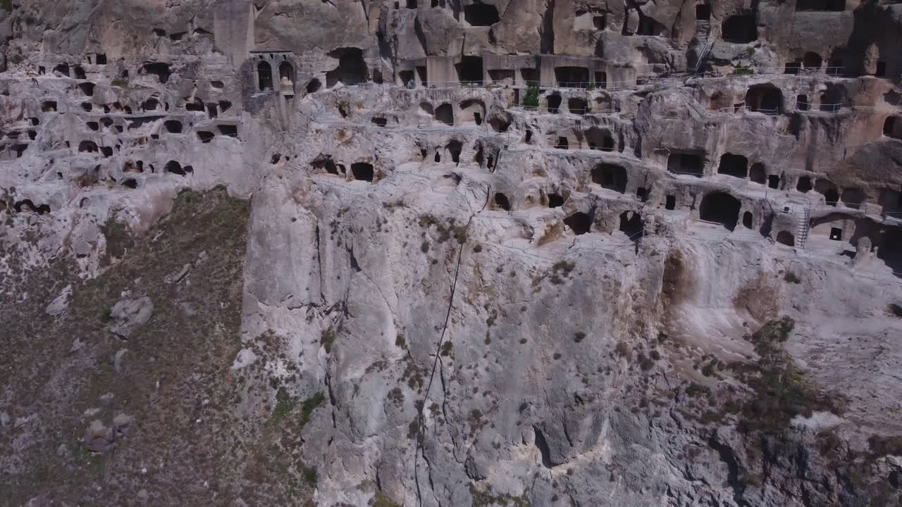 Aerial shot of the ancient Vardzia cave monastery in southern Georgia. The medieval structure is carved into the cliffs and features tunnels, rooms, and terraces.