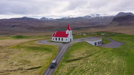 aerial over a black camper van driving up to a church on a hill in the mountains of iceland 3