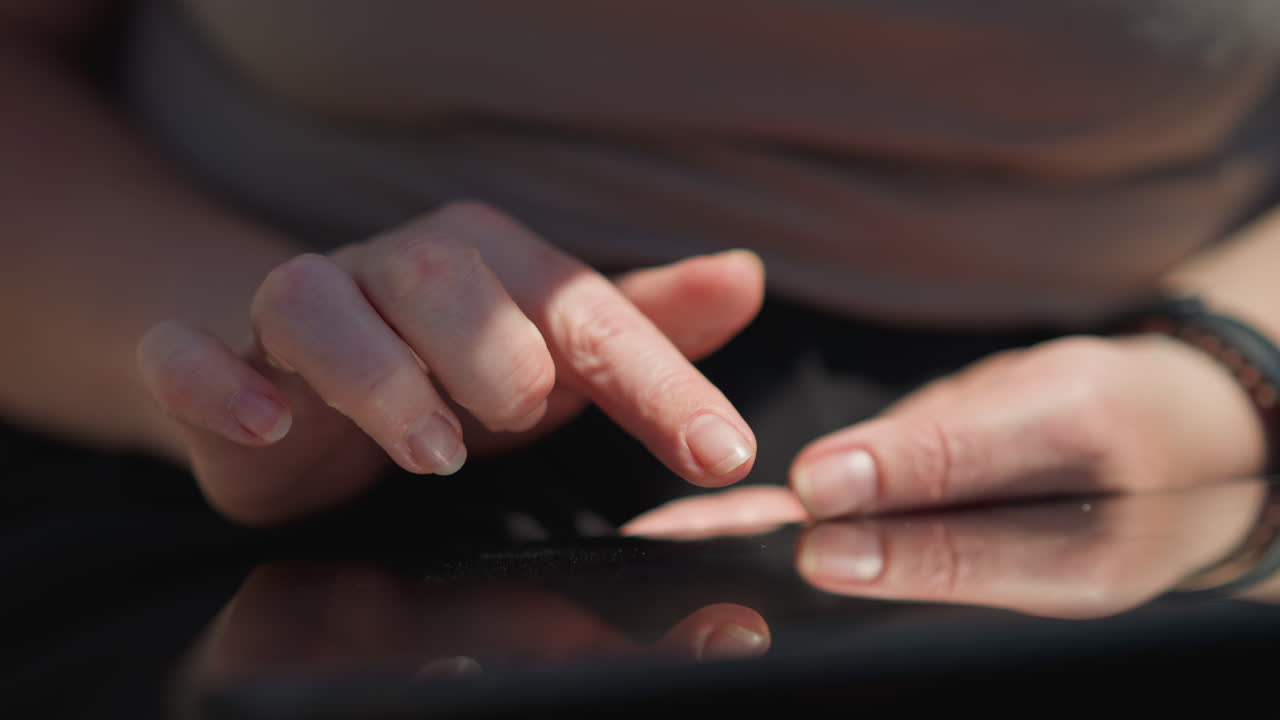 Close up of lady hands sliding through phone screen in warm sunlight, gentle touch over glass with soft reflection, calm outdoor moment with focused navigation