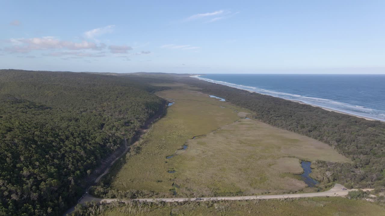 conducción de automóviles en alfred martin way cerca del parque nacional blue lake con vistas al mar de coral - isla de stradbroke del norte, qld, australia