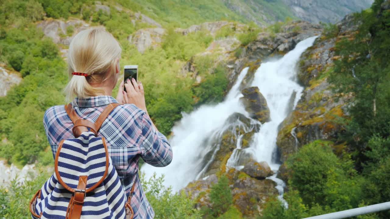 mujer viajera toma fotografías de una pintoresca cascada en noruega glaciar briksdal el majestuoso sc