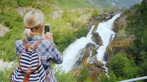 mujer viajera toma fotografías de una pintoresca cascada en noruega glaciar briksdal el majestuoso sc