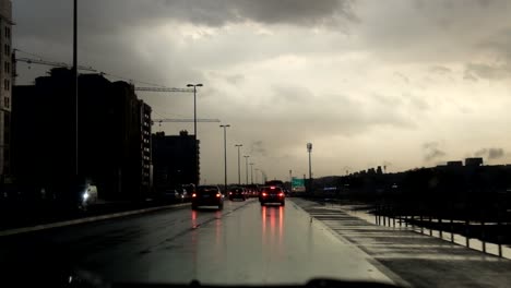 windshield first person view of road traffic during early morning sunrise with clouds under heavy rain in a highway of dubai, united arab emirates on november 26, 2018