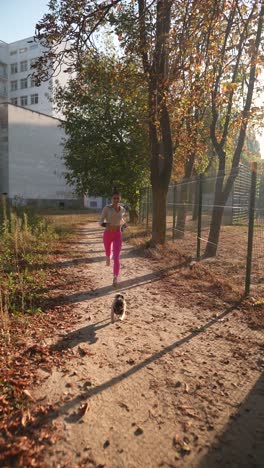 mujer corriendo con su perro en un parque durante el otoño