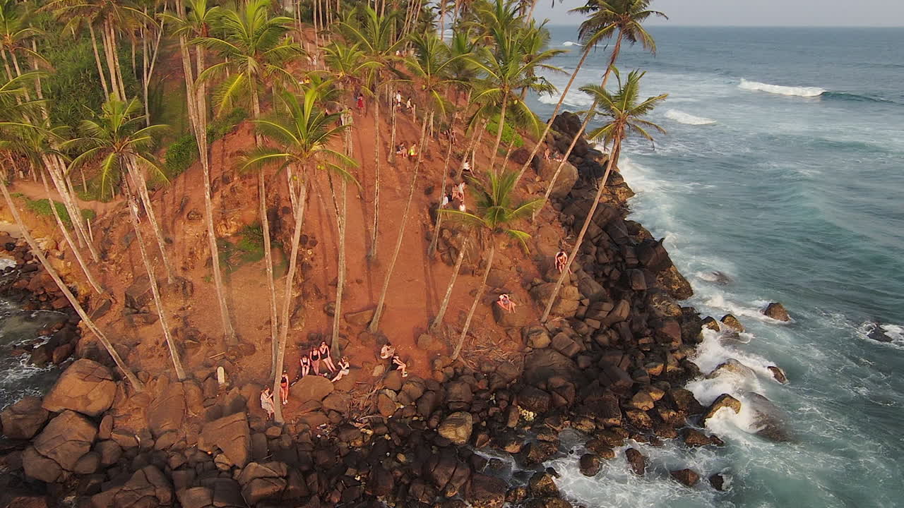 Ripresa orbitale FPV di persone che si godono la brezza marina su una piccola e bellissima collina rocciosa, Sri Lanka