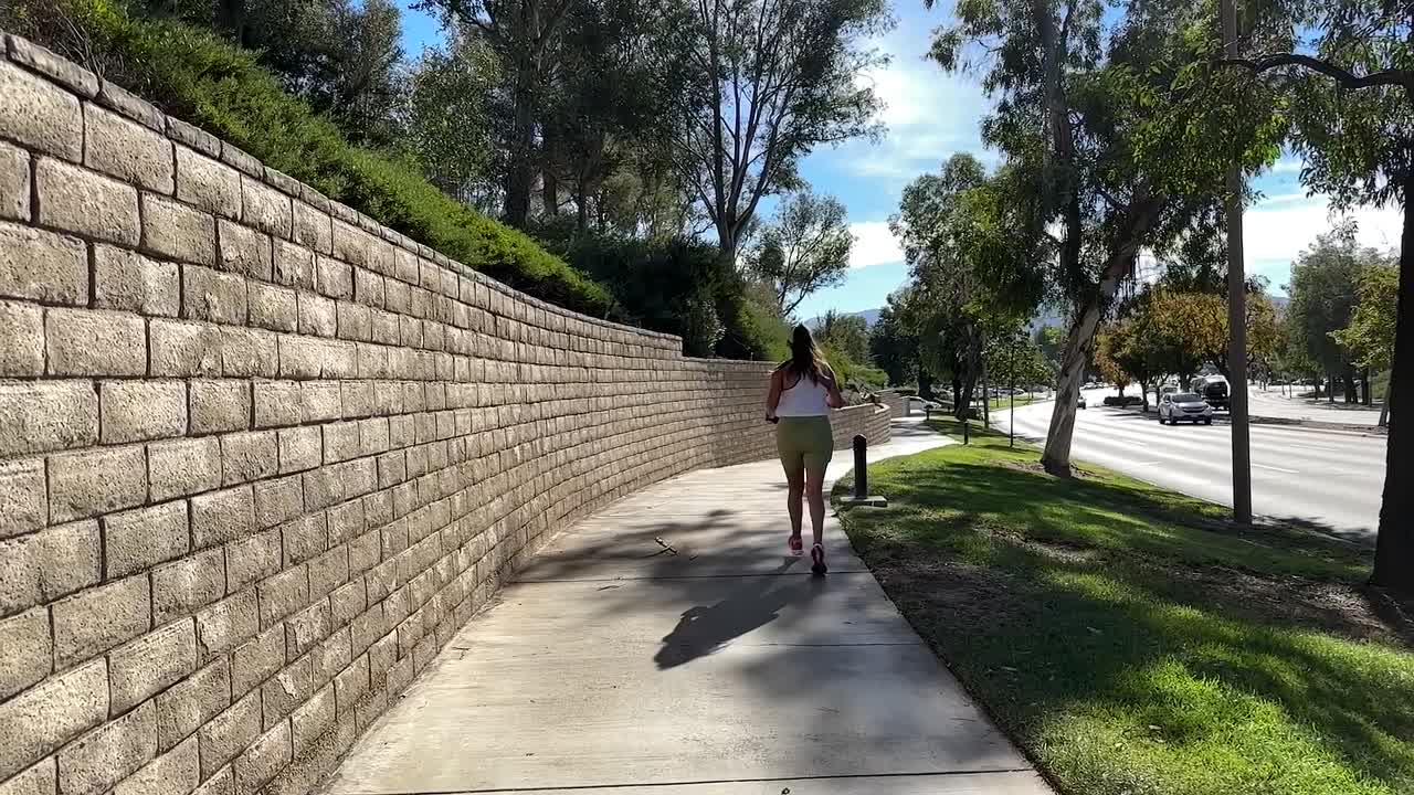 corredora trotando a lo largo de la acera en un día soleado