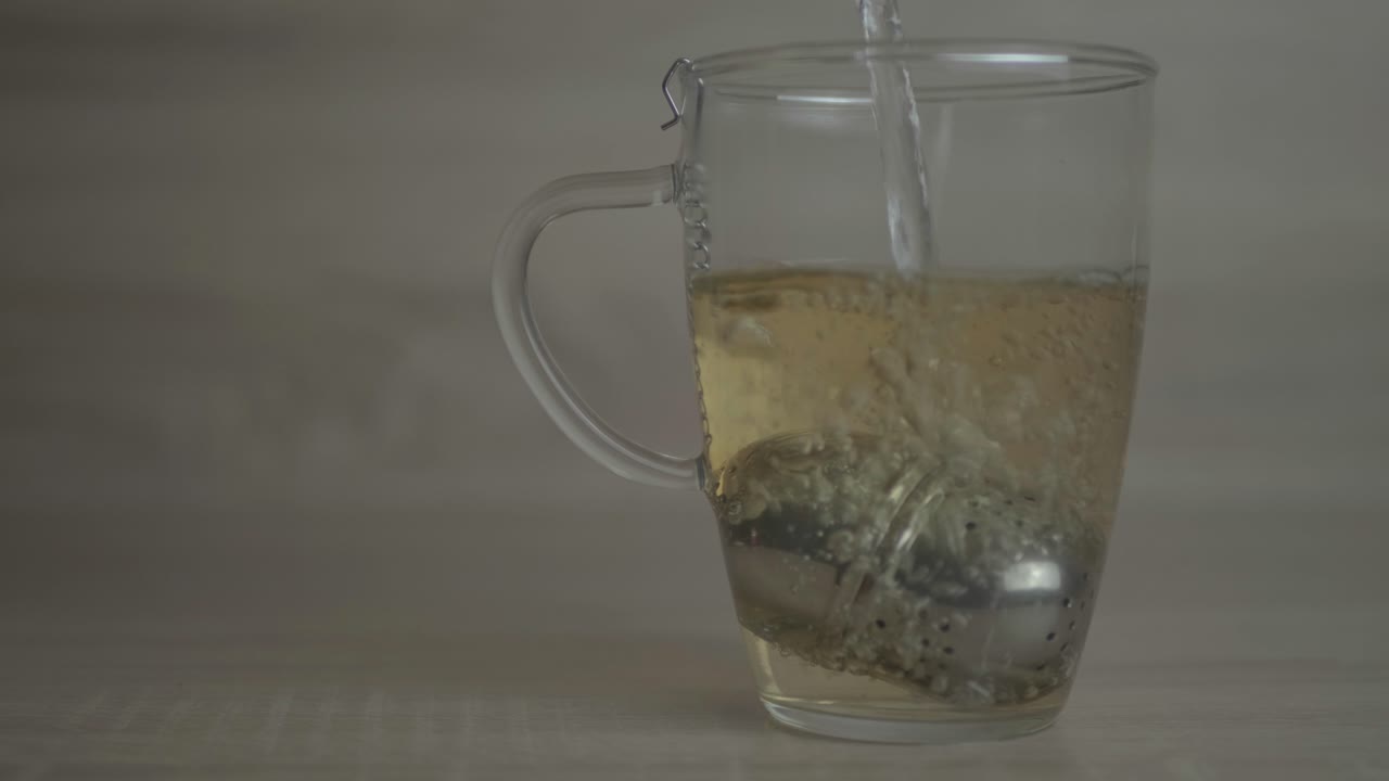 Hot Water Slowly Poured Inside A Tea Cup With A Stainless Infuser- Gives An Aromatic Smell That Will Capture Your Heart - Close Up Shot