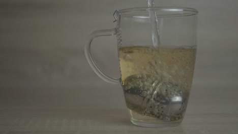 hot water slowly poured inside a tea cup with a stainless infuser- gives an aromatic smell that will capture your heart - close up shot