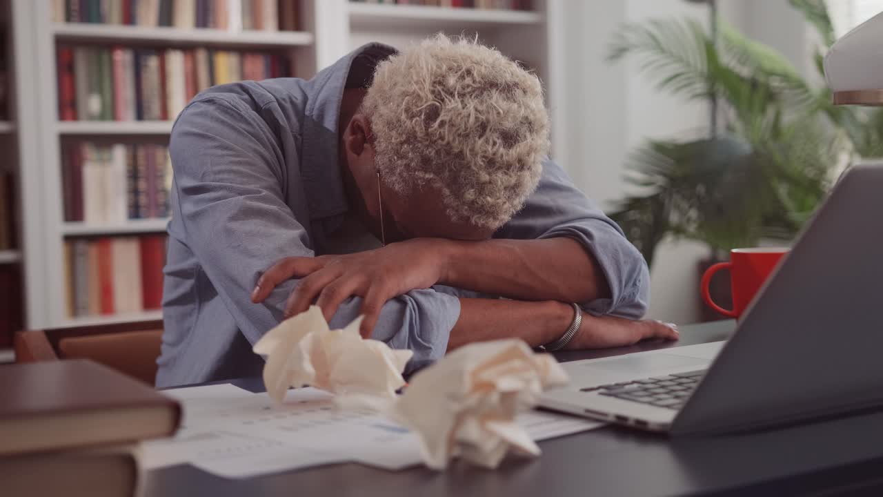 Tired african american man rested head on table due to overwork