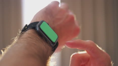 close up de un hombre sentado en la cama mirando la pantalla de un reloj inteligente