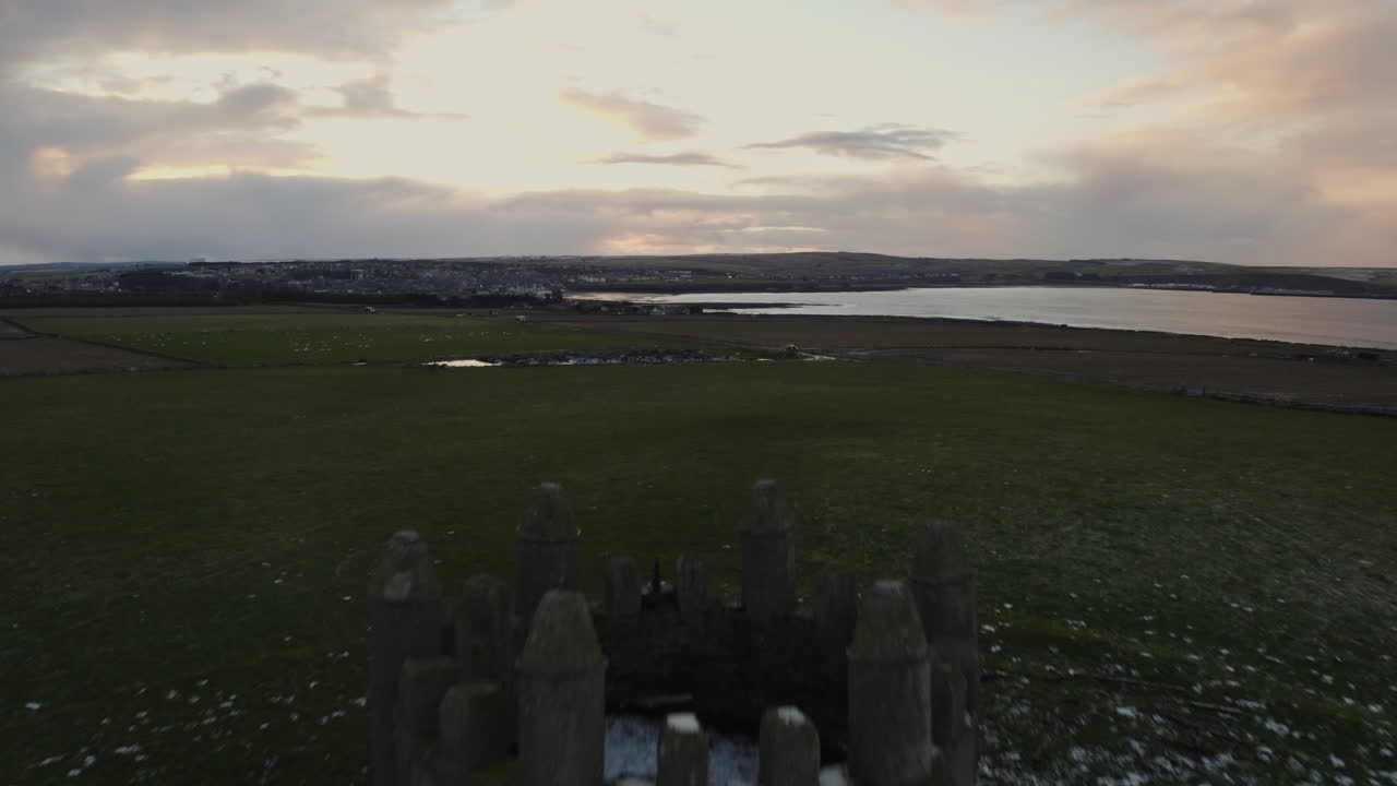 Stone cottage on grassy hillside under foggy skies in rural Wild Atlantic Ireland, aerial approach