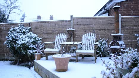 snow fall in english garden chimnea and bench seat early morning winter