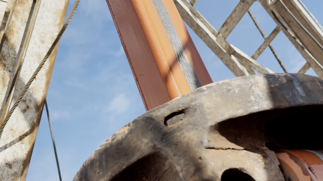 Rotating pole hanging from the derrick drilling the ground. Low angle view. Natural resources production.