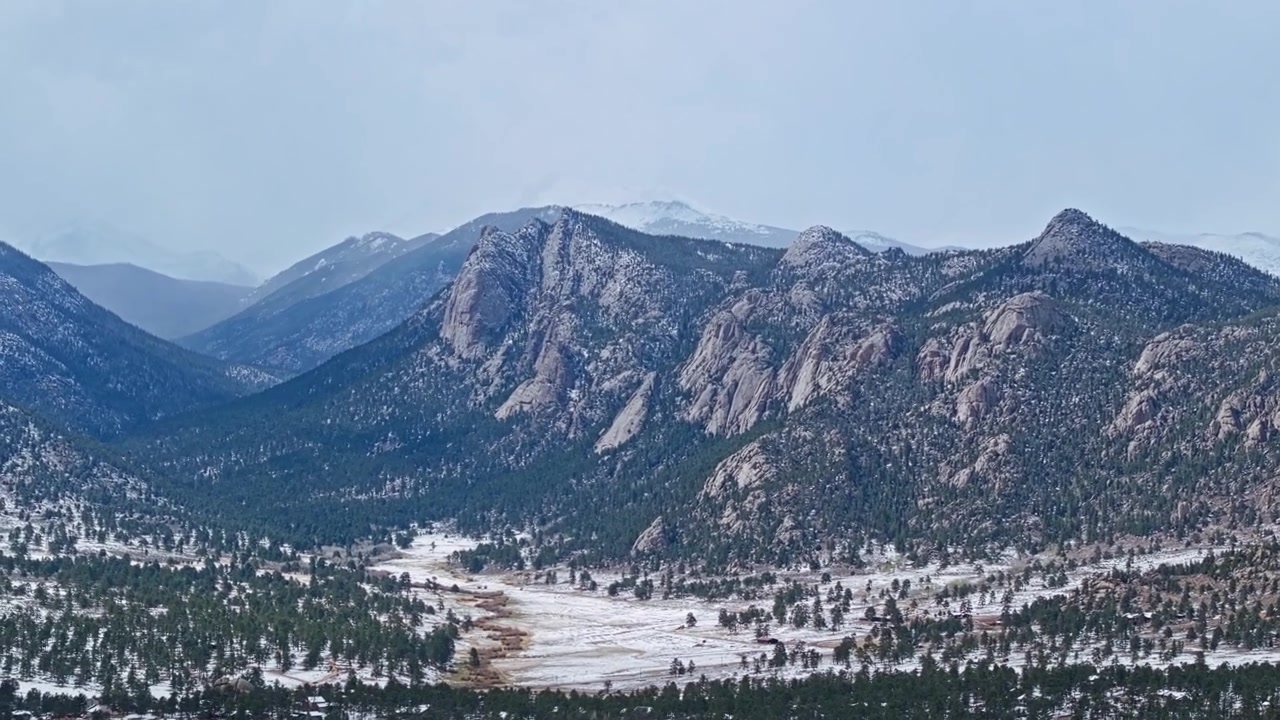 Città e valle di Estes Park con le Montagne Rocciose innevate e paesaggio forestale, panoramica aerea con drone.