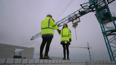 architect and foreman in construction site woman inspector is giving documentation to civil engineer