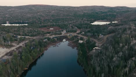 Vista-Panorámica-Aérea-Del-Lago-Del-Bosque-Con-Cabañas-Junto-A-La-Orilla-En-Saint-come,-Quebec,-Canadá