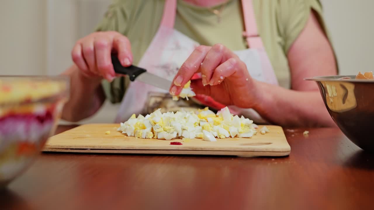 Elderly woman slicing eggs, slow motion inside warm traditional Latvian kitchen
