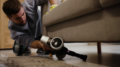 man cleaning under the sofa