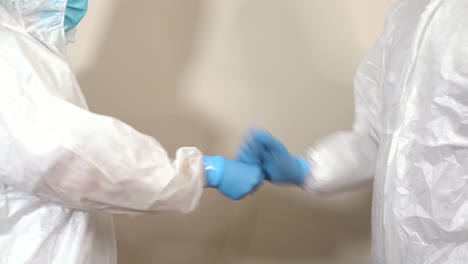doctors in ppe suits rehearsing friendly greeting each other with fists