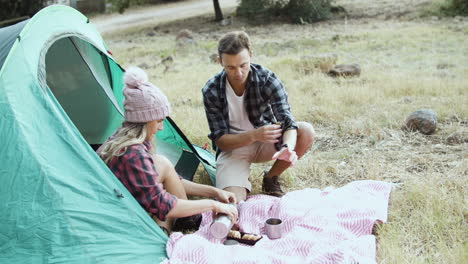 Camping couple eating breakfast, drinking tea or coffee