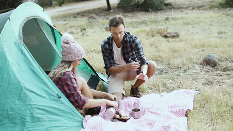 camping couple eating breakfast, drinking tea or coffee