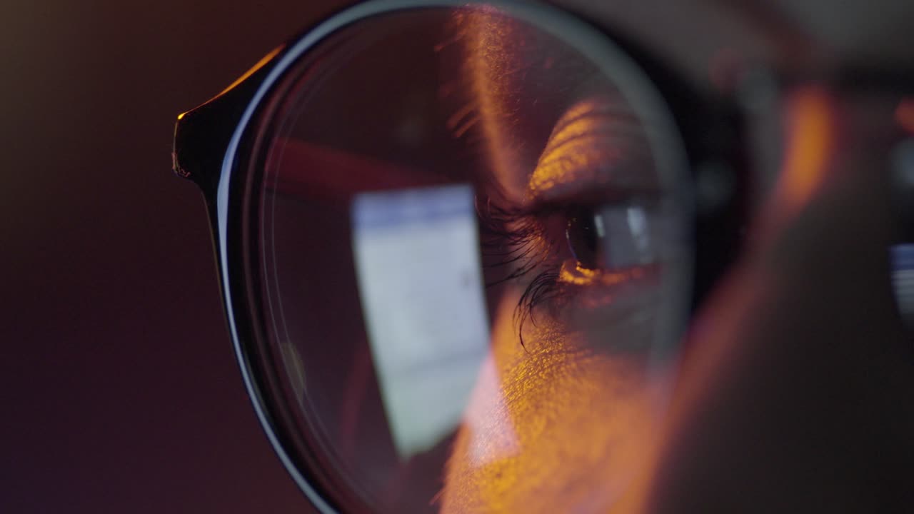 persona con gafas mirando una pantalla de computadora por la noche