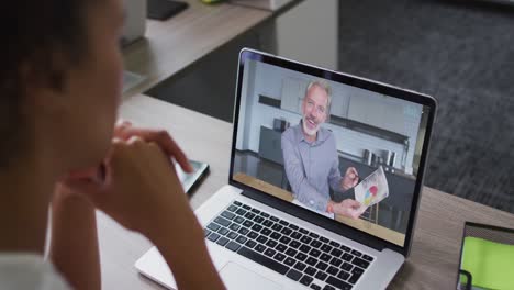 Mid-section-of-african-american-woman-having-a-video-call-with-male-colleague-on-laptop-at-office