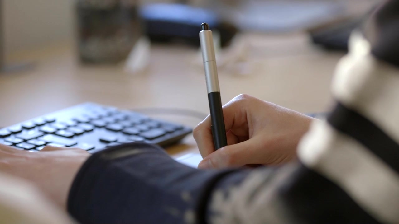 Closeup of young designer spinning and using a stylus pen with graphics tablet