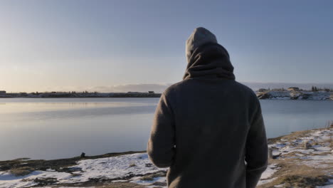 Follow-shot-of-young-male-travel-walking-at-scenic-lake-while-drinking-coffee