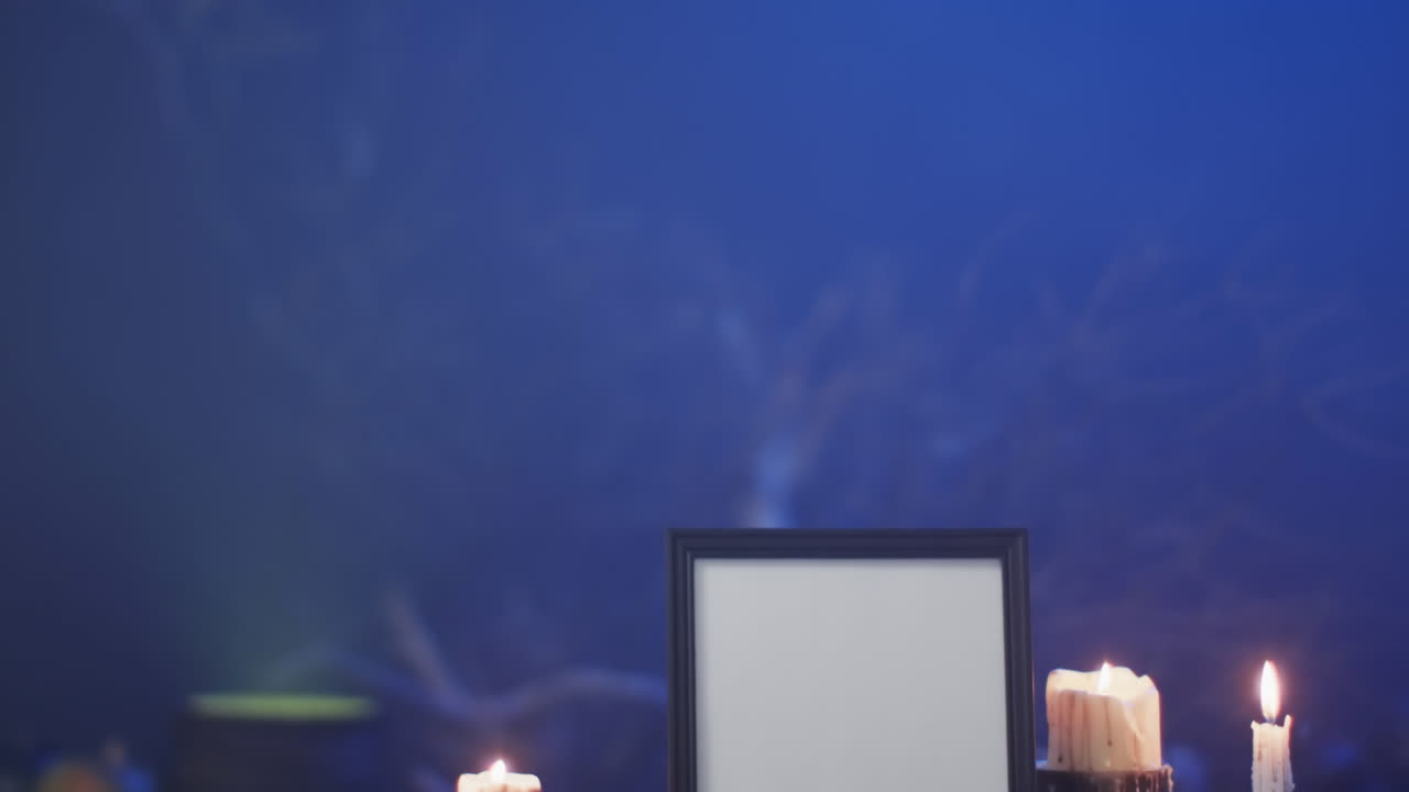 video de un marco con espacio de copia, tela de araña, cráneo y velas sobre fondo azul