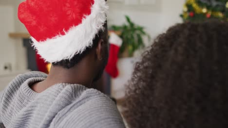 Back-view-of-african-american-couple-sitting-on-sofa-at-fireplace