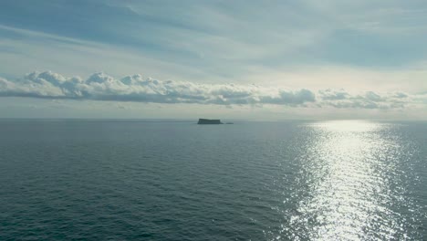 Vuelo-Aéreo-Lento-Hacia-La-Isla-De-Filfla-Frente-A-La-Costa-De-Malta-En-El-Océano-Mediterráneo-Siguiendo-El-Sol-Brillante