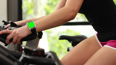 mujer en forma usando bicicleta de ejercicio y reloj inteligente