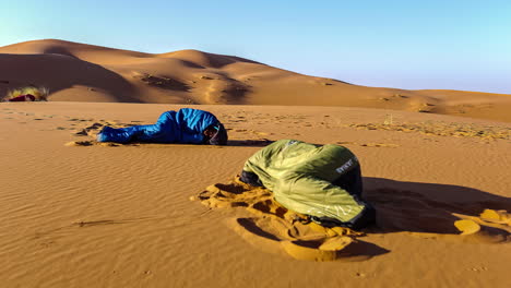 Dos-Personas-Durmiendo-En-Sacos-De-Dormir-En-El-Desierto