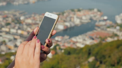 Weibliche-Hände-Mit-Einem-Smartphone-Benutzen-Das-Telefon-Vor-Dem-Hintergrund-Der-Stadt-Bergen-4k-Video